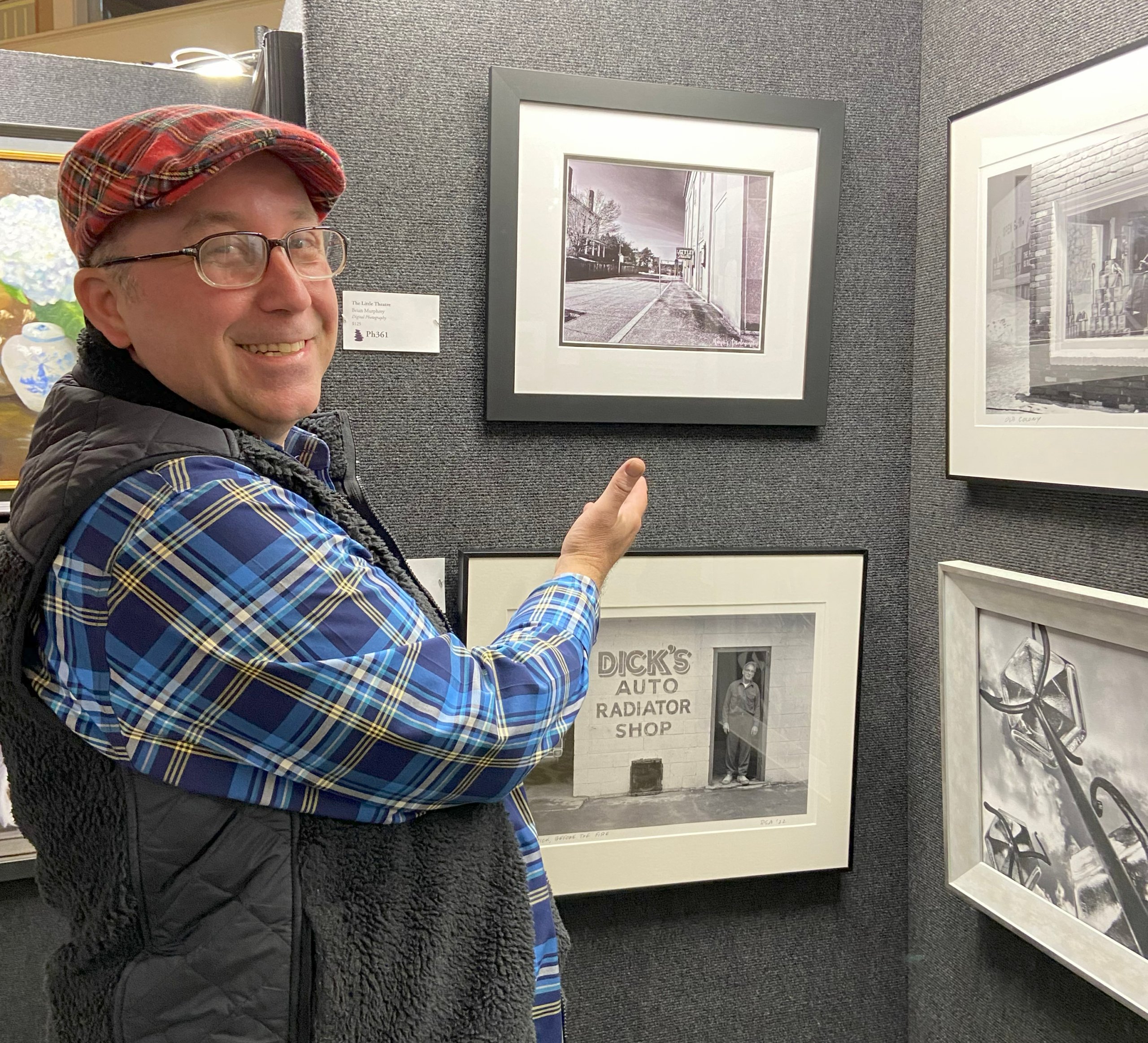 Man pointing to his artwork hanging on a wall