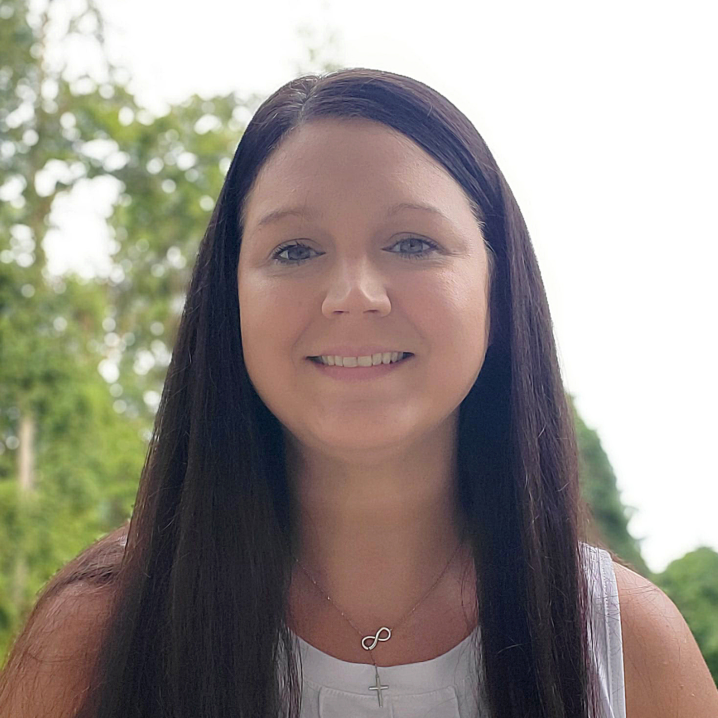 Ashleigh Hesler has straight long brown hair, white top and is smiling