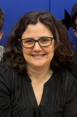 Meaghan is smiling and has dark hair, wears glasses is wearing a dark top